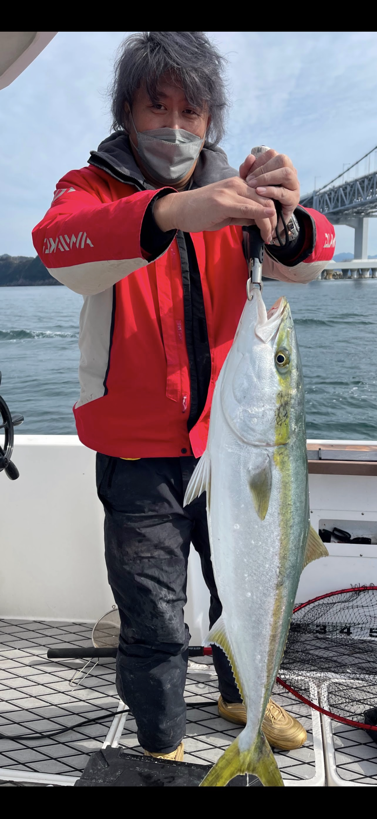 船上で釣れた魚を持つ写真